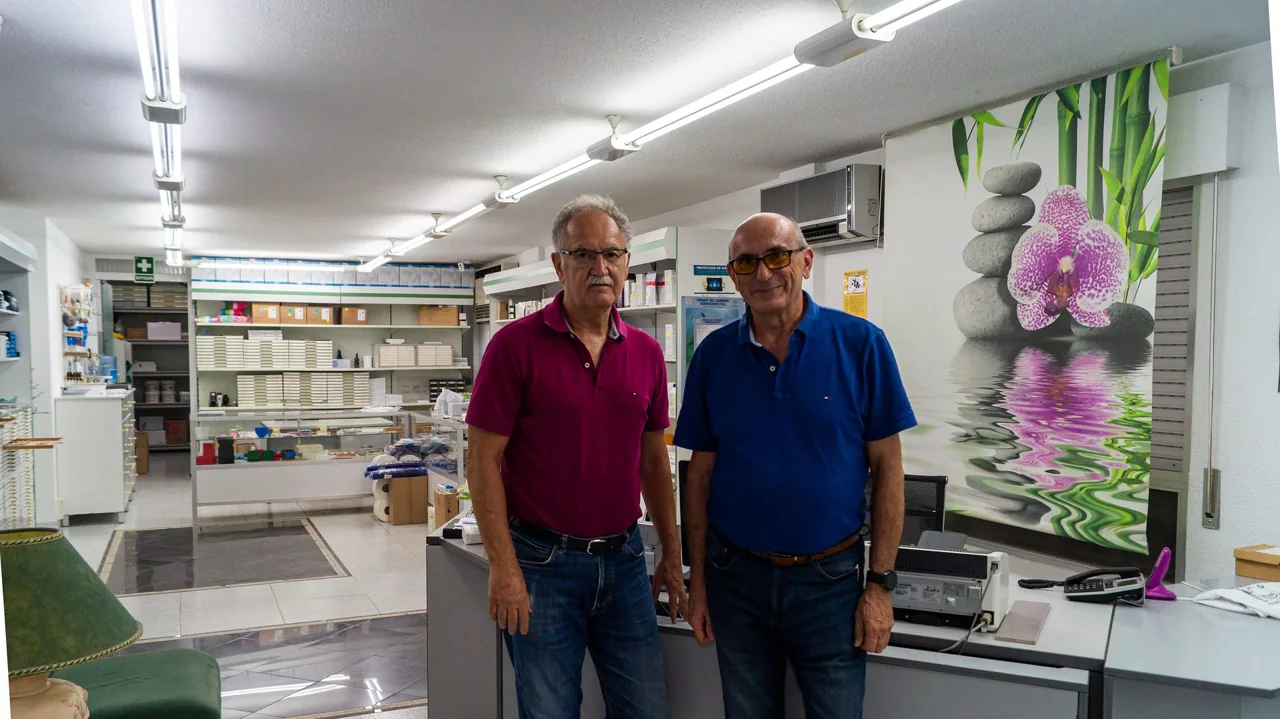 Dos personas en el interior del depósito dental García Torres, junto al mostrador y las estanterías de material